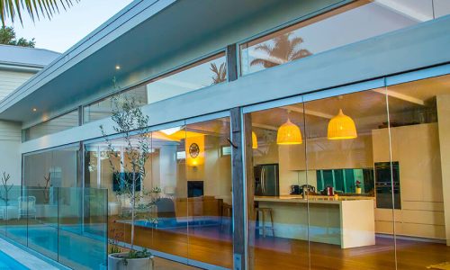 Ecolux Low-E dual-climate architectural window film by Solar Gard on a glass wall looking into a modern kitchen.