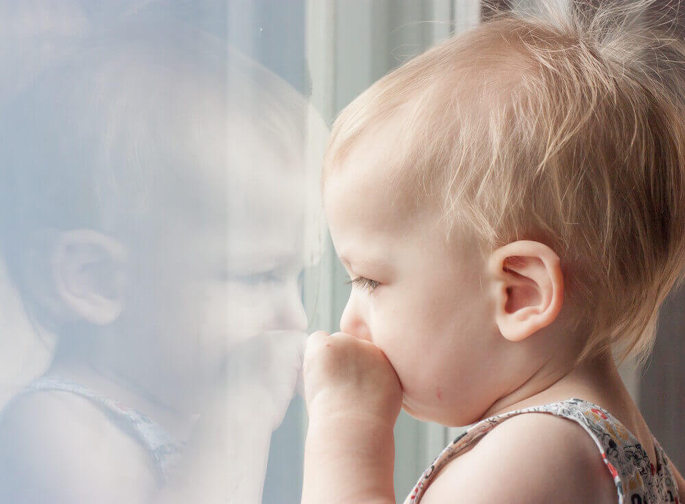 child gazing out home window