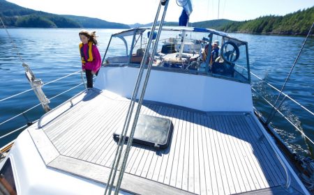 Family on vacation sailing Desolation Sound in sail boat on calm sunny day through the wilderness marine landscape.